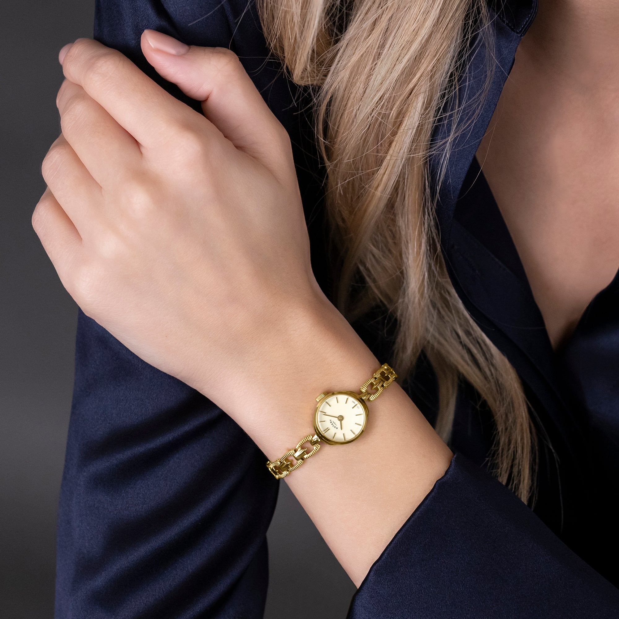 Gold Rotary watch on a woman's wrist with a dark background
