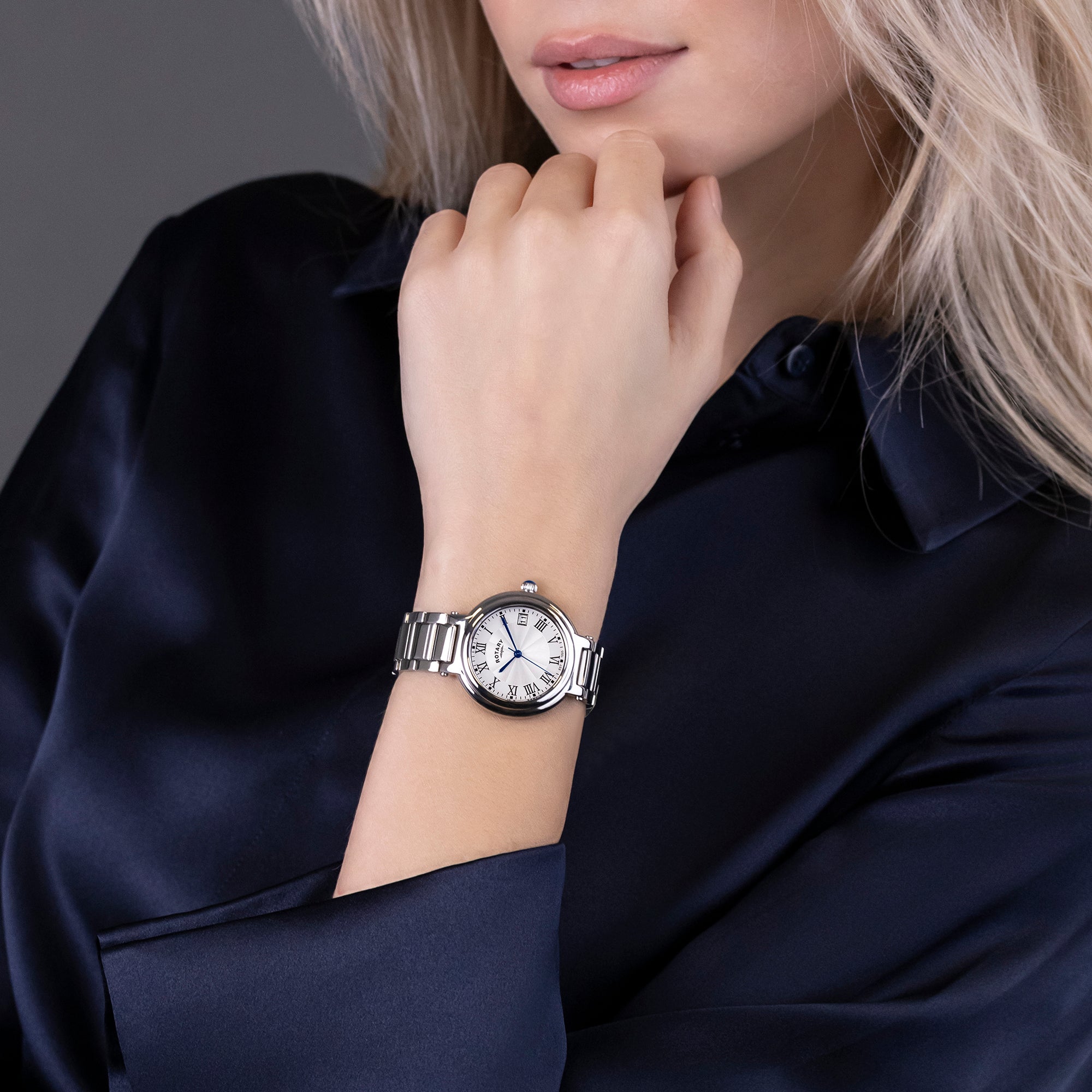 Woman wearing a silver Rotary watch on a dark background