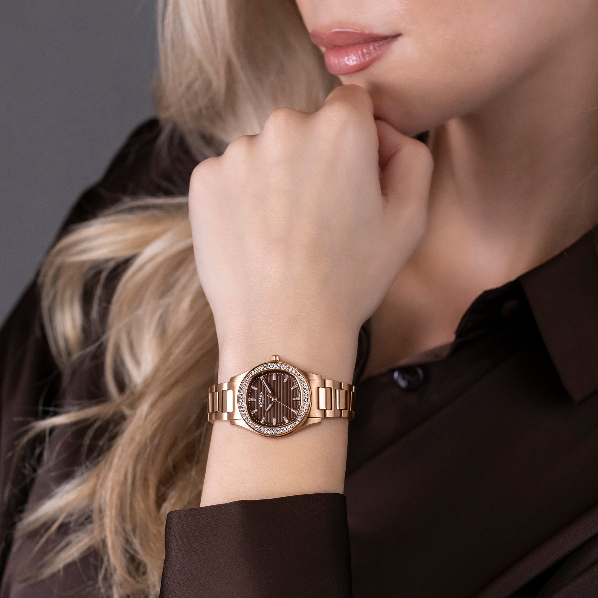 Woman wearing a rose gold Rotary Brilliance watch with a blurred background