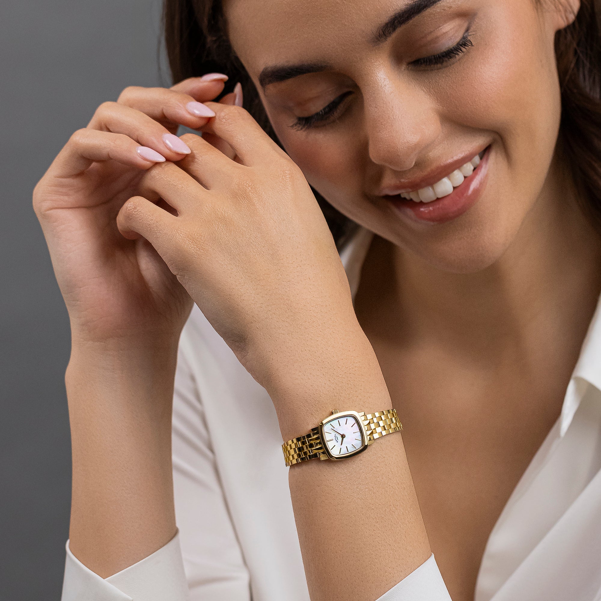 Woman wearing a gold Rotary Heritage Astoria watch with a white background