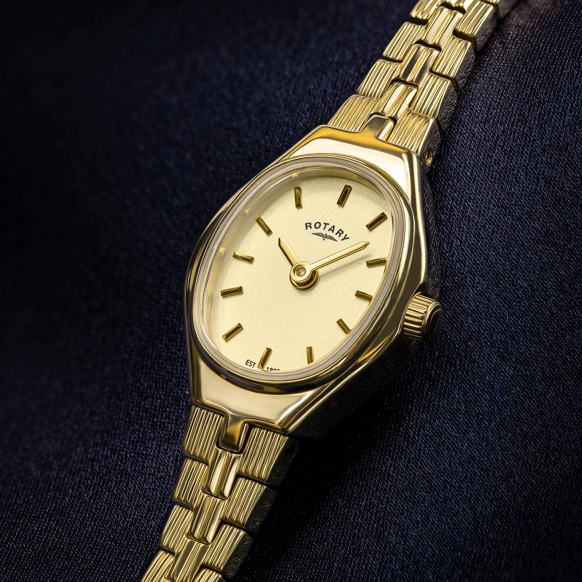 Ladies gold Rotary 1895 watch on a dark fabric background