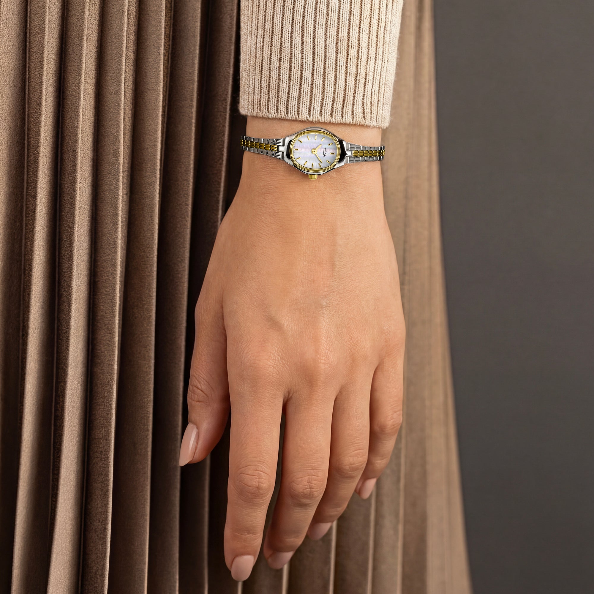A woman wearing a two-tone Rotary ladies watch with a neutral background