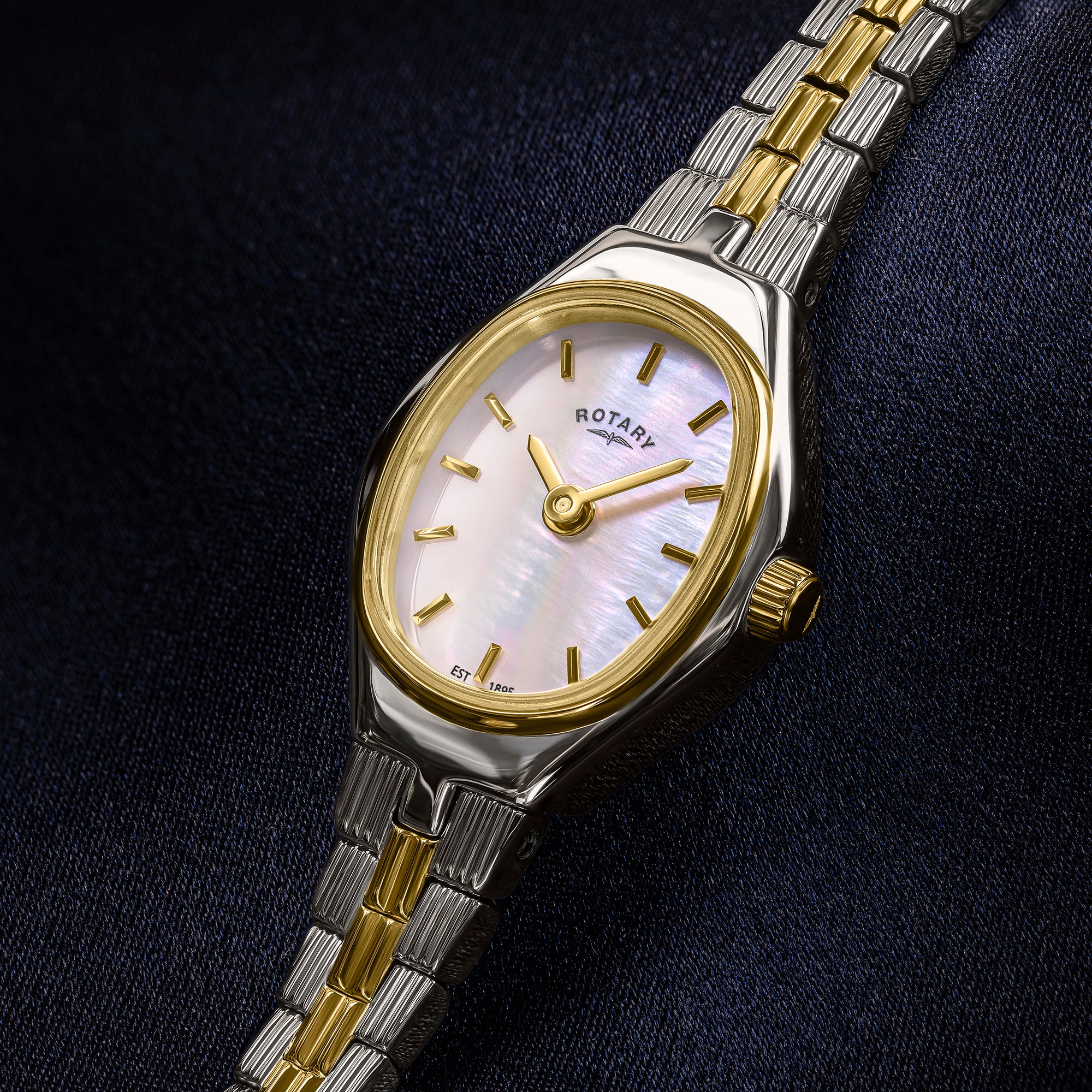 Two-tone Rotary 1895 watch on a dark fabric background