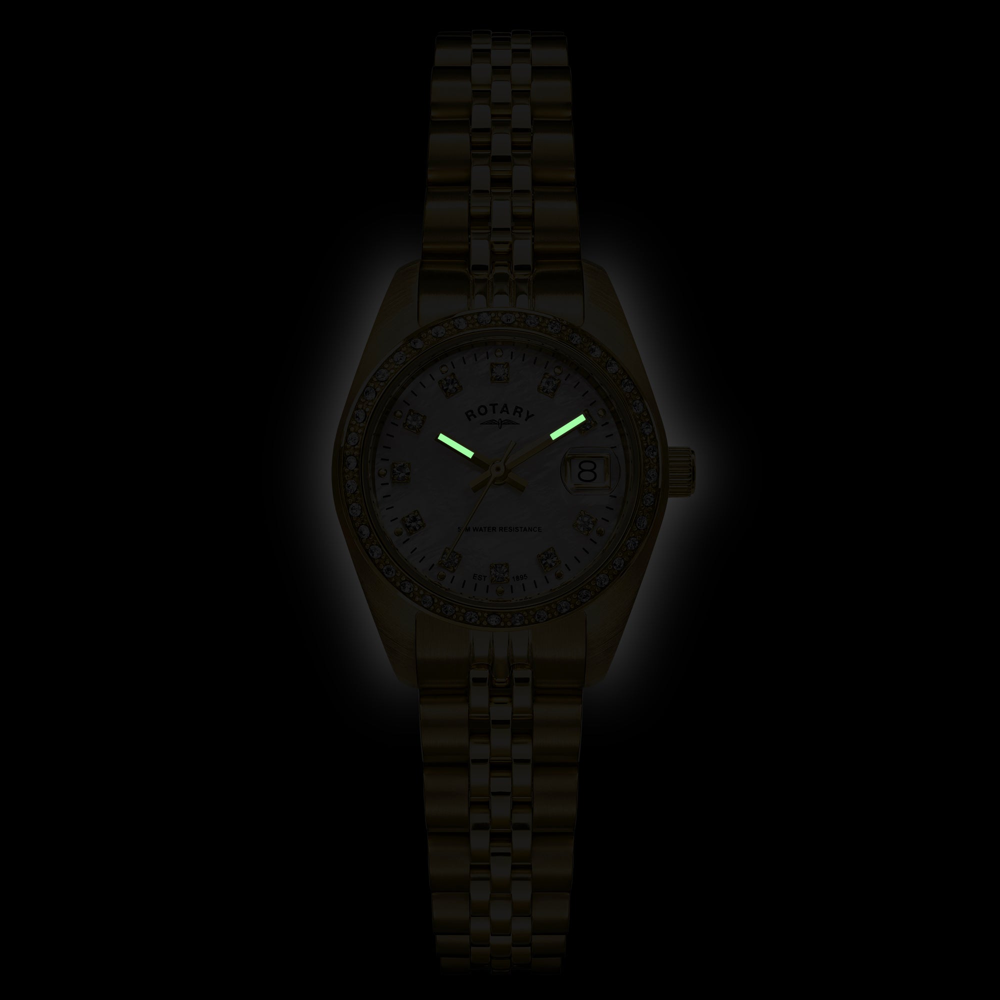 A Rotary Dress Date wristwatch with a metallic case and link bracelet, featuring glowing green hands and a light-colored dial with gem-set hour markers, shown against a black background.