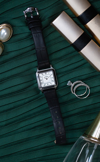 A ladies rotary dress watch on a dressing table with various jewellery surrounding it