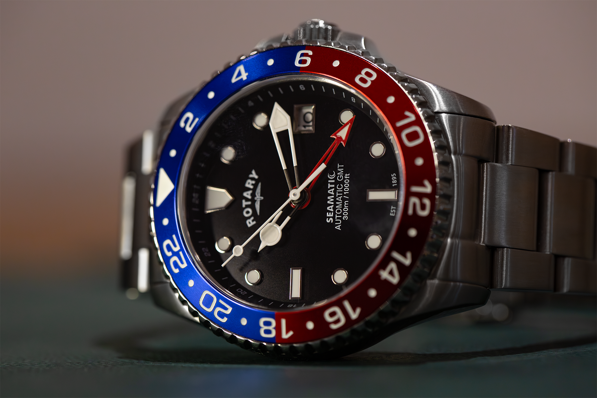 Rotary Seamatic GMT watch with a distinctive black, red, and blue bezel on a blurred background