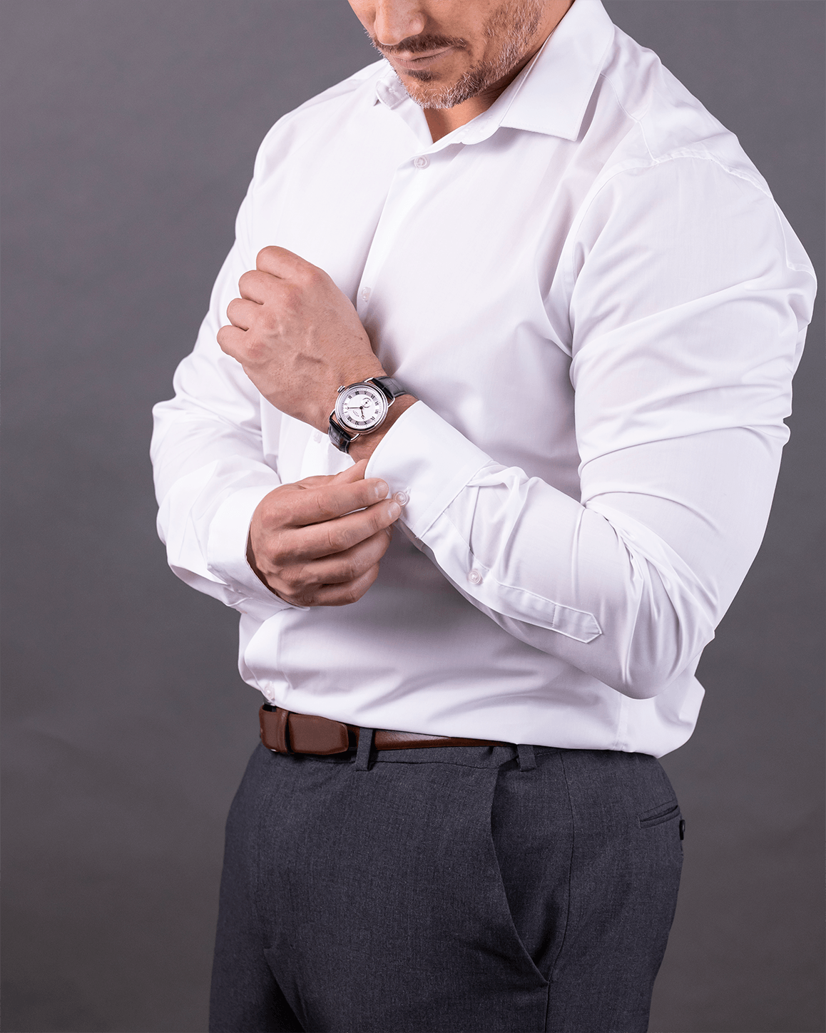 Man adjusting his white shirt against a gray background wearing a Rotary Sherlock watch