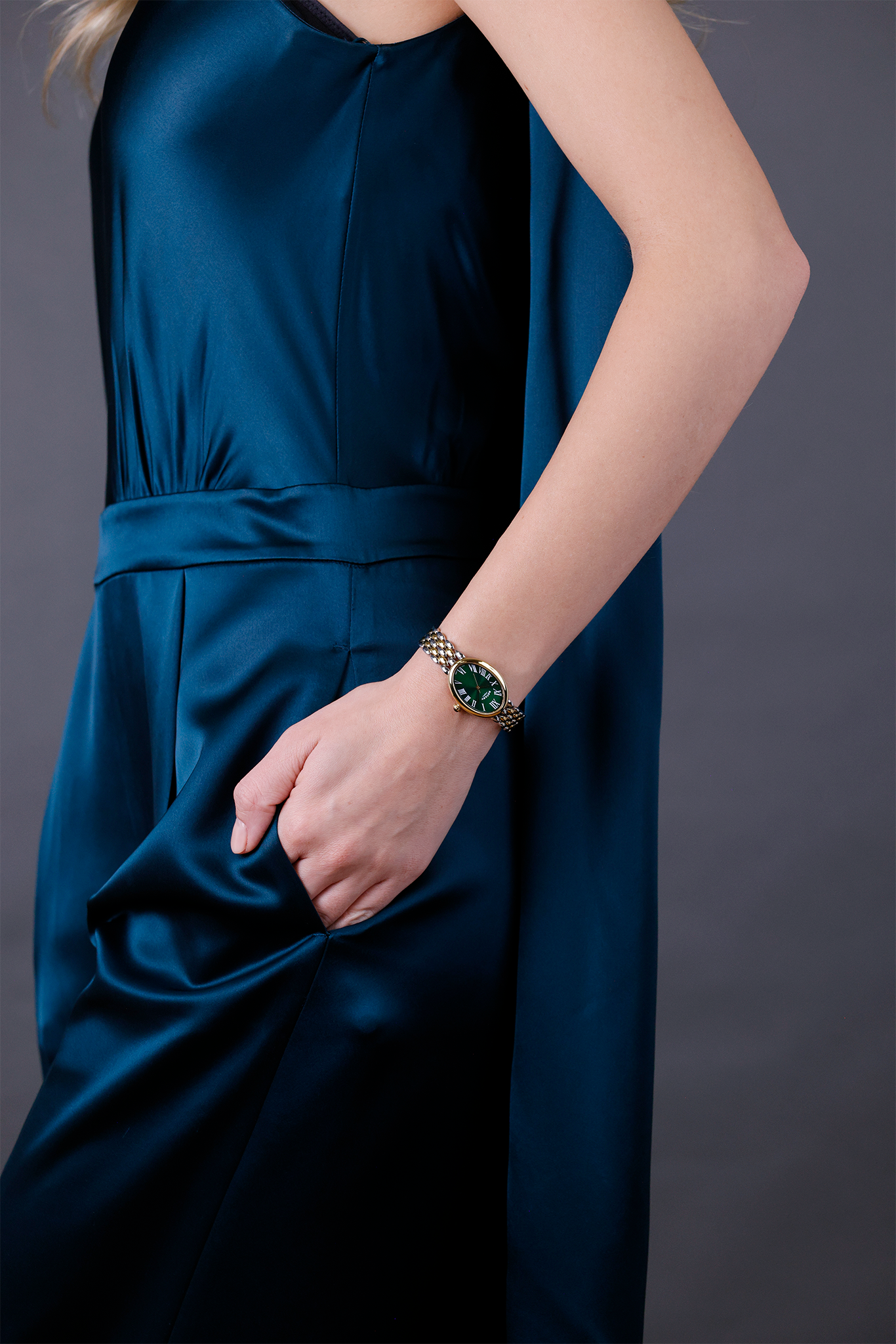 Woman wearing a blue dress with a green Rotary Heritage Astoria watch on a gray background