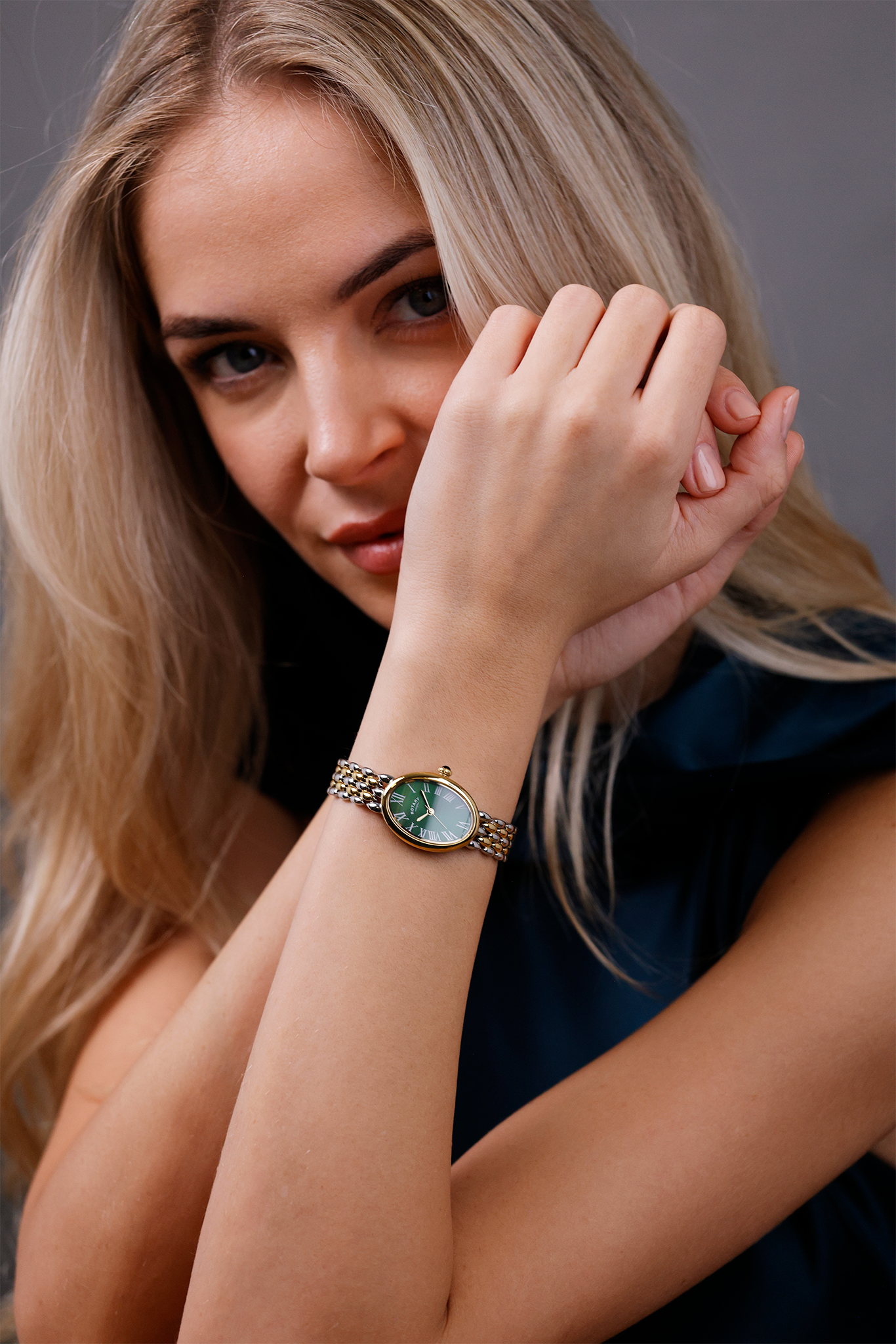 Woman wearing a Rotary Heritage Astoria watch with a green dial on a gray background