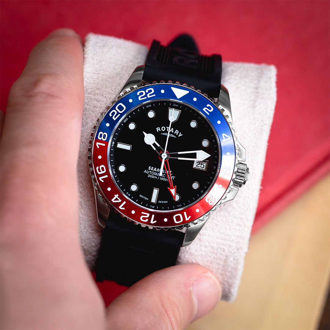 rotary seamatic gmt watch with a blue and red bezel, black dial and a black silicone dive strap. The watch is placed on a watch roll and is being picked up by a man